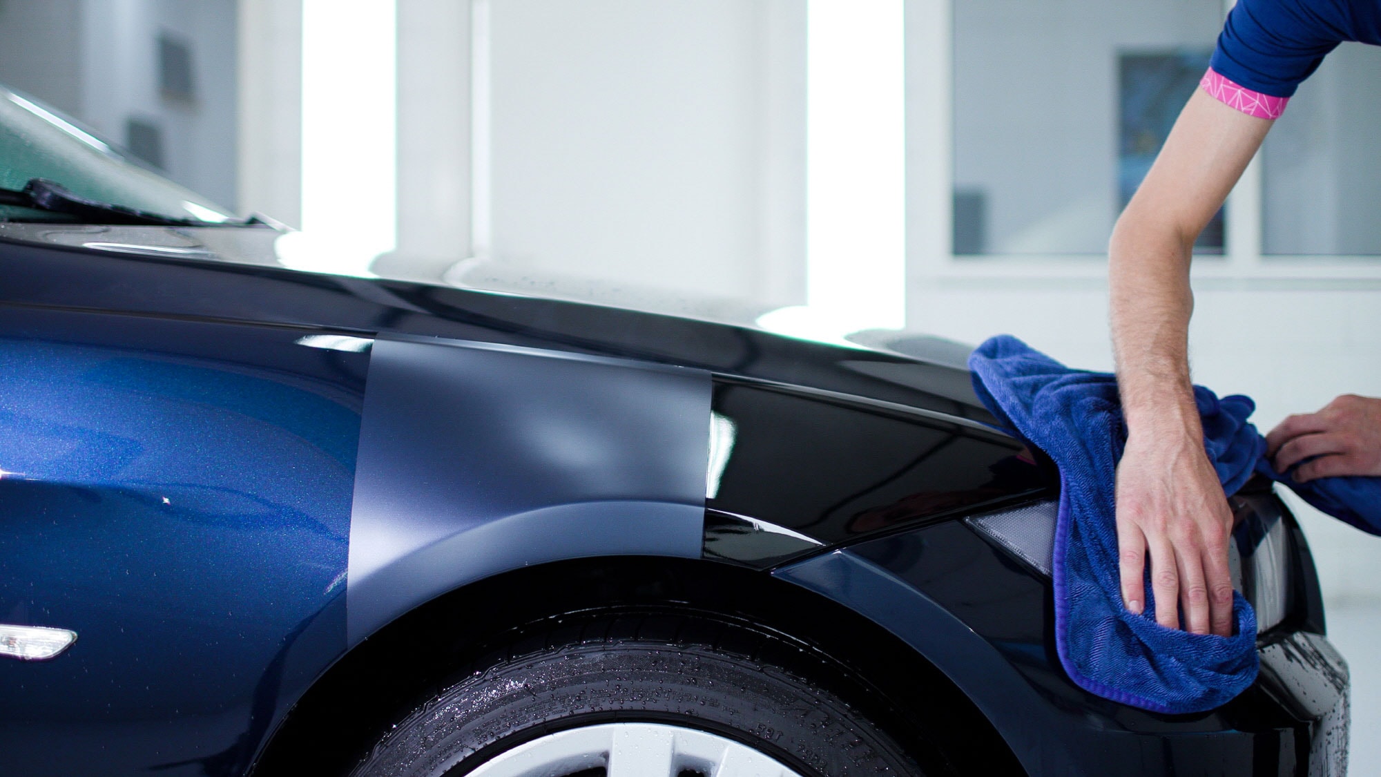 Matte and gloss film samples on a blue car fender in GYEON's PPF catalogue photograph.