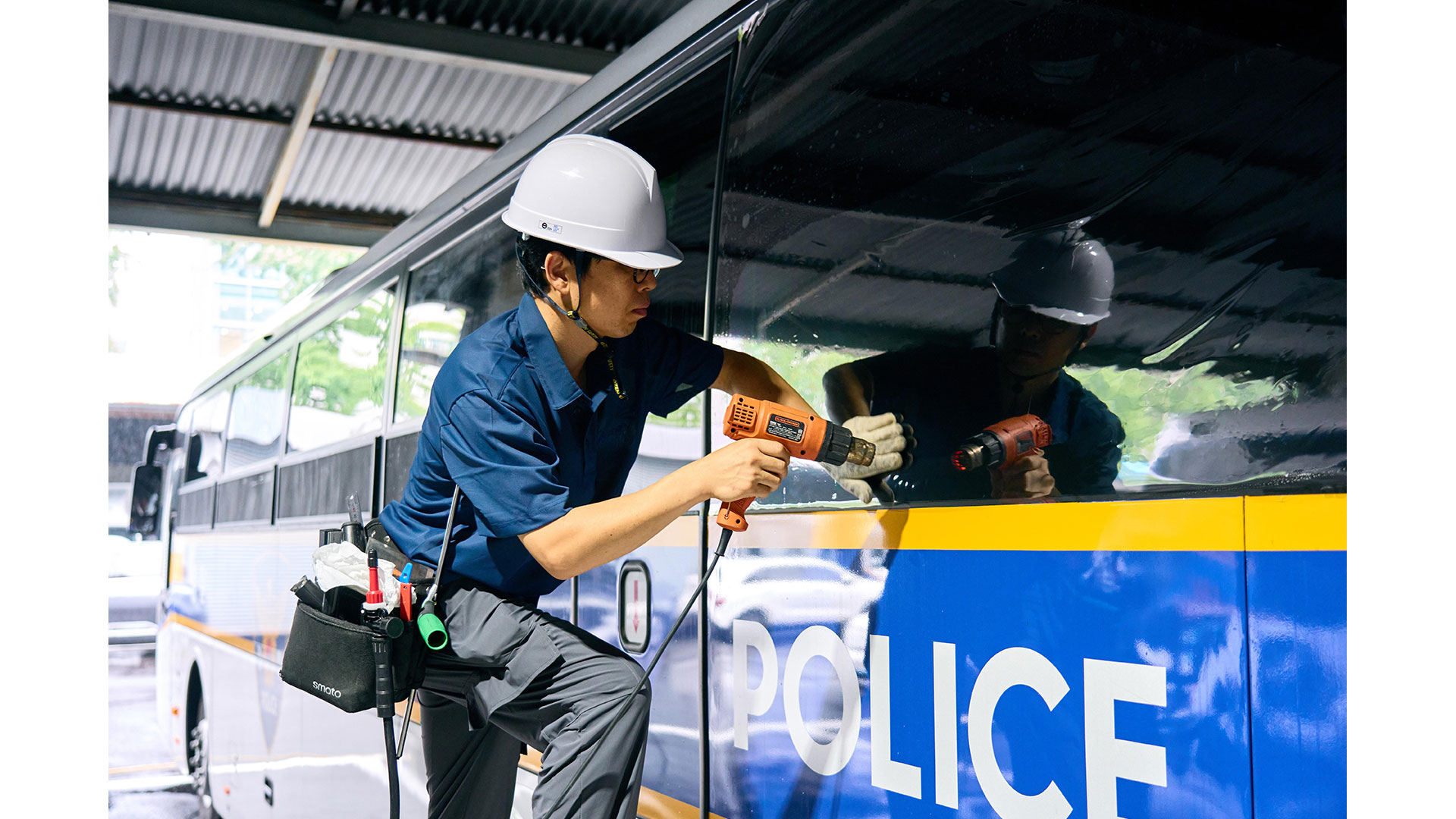 Worker applying film to a police bus window.