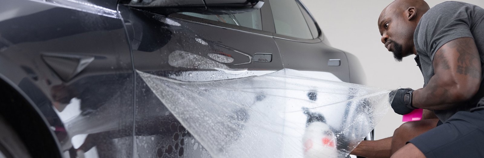 A LLumar installation photograph showing clear paint protection film being fitted to a car door.